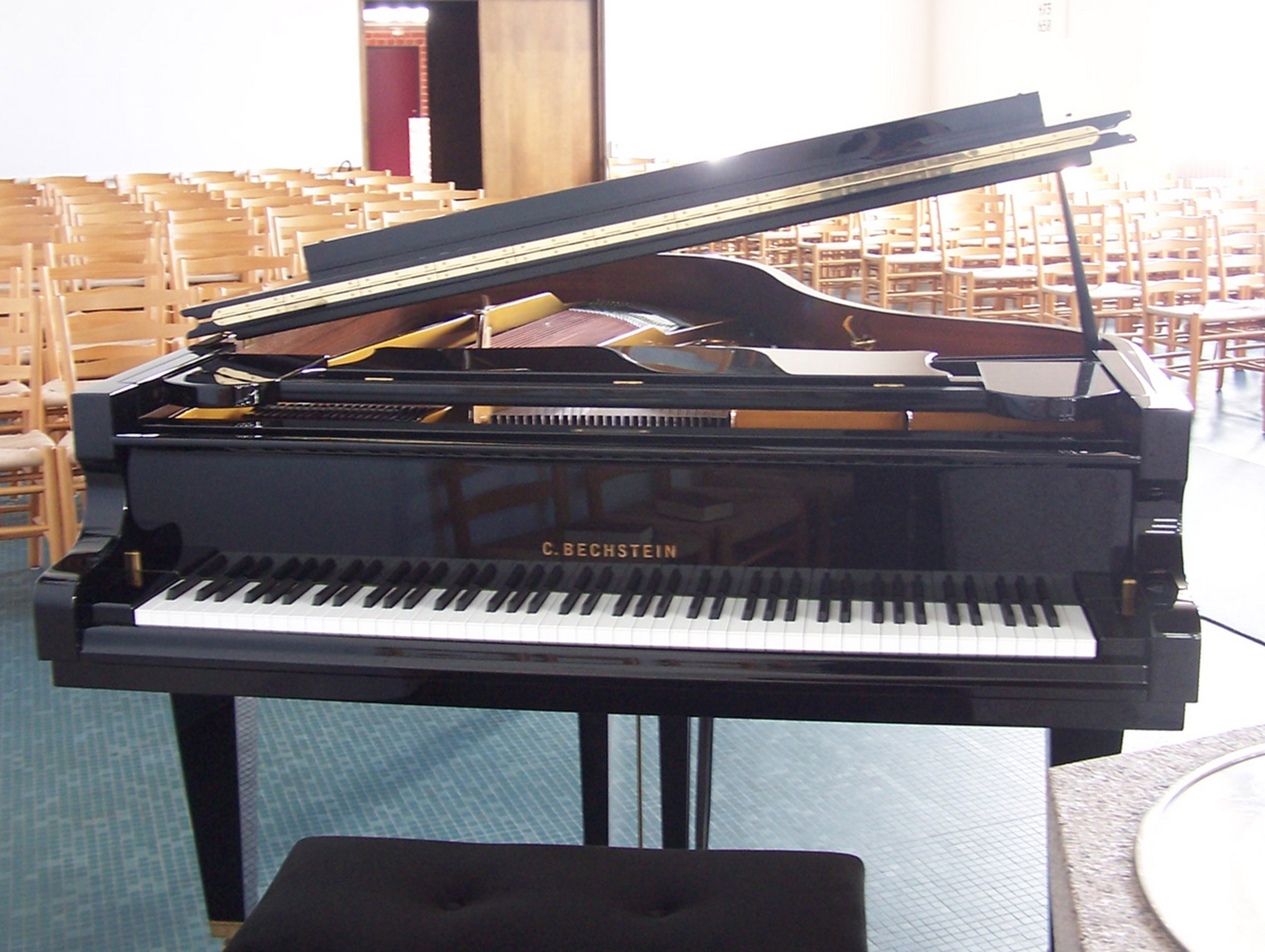 Schwarzer C. Bechstein Flügel in einem Kirchenraum mit Bestuhlung im Hintergrund.