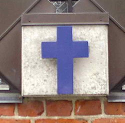 Et blåt kors-symbol monteret på en murstensvæg.