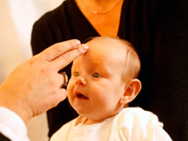 En baby, der bliver døbt med vand på hovedet.