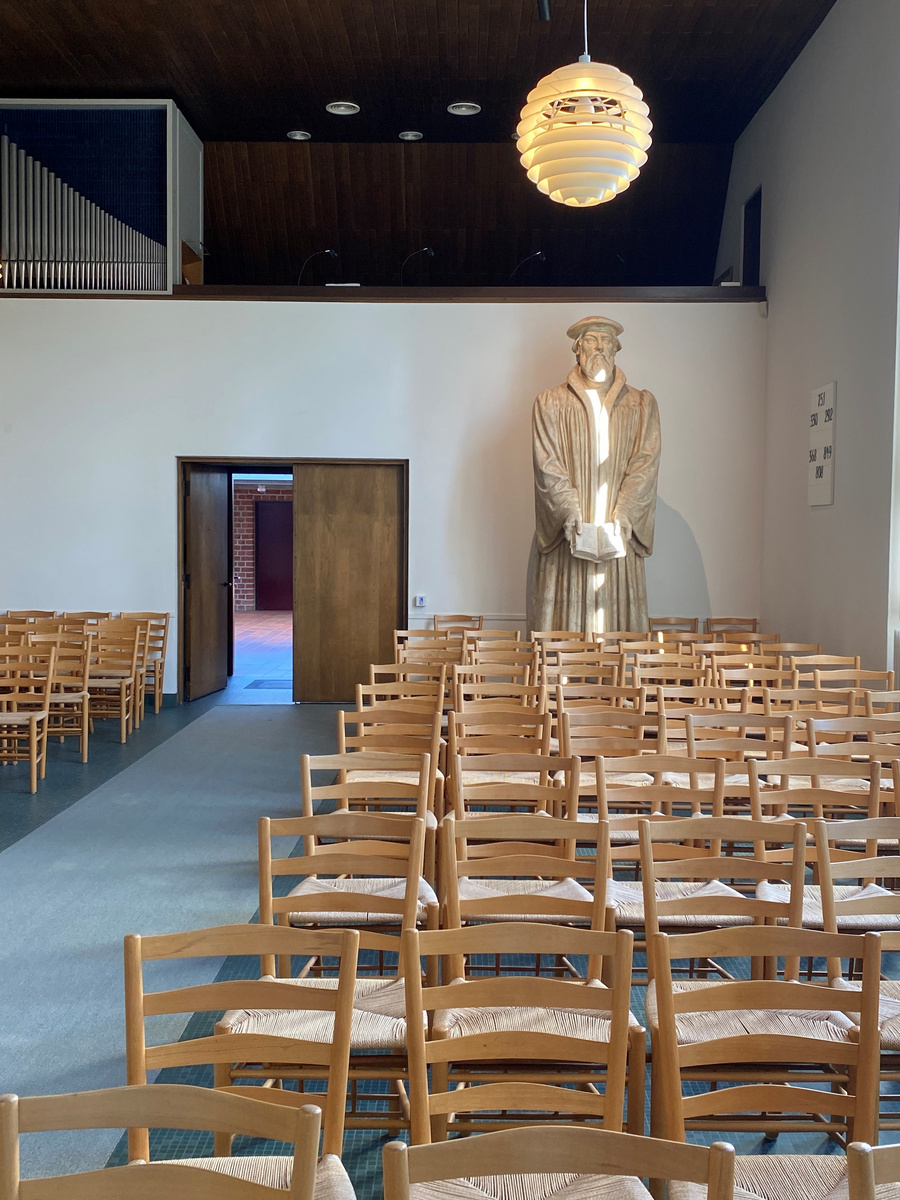 Kirkesal med træstole og en statue af Martin Luther.