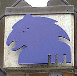 Et blåt vinget løve-symbol (Markusevangeliet) monteret på en murstensvæg.
