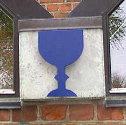 Et blåt alterkalk-symbol på en murstensvæg.