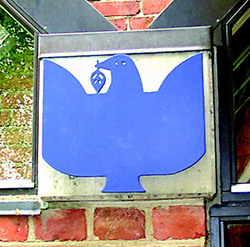 Et blåt due-symbol monteret på en murstensvæg.